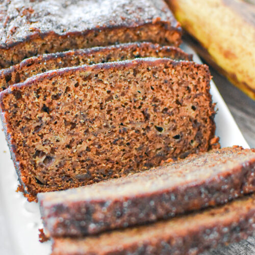 Loaf of Moist Banana Bread on a plate near a banana