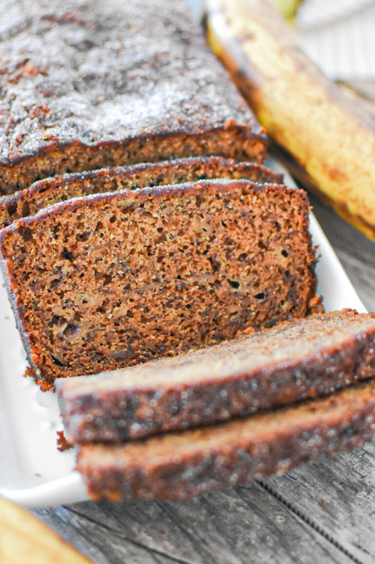 Loaf of Moist Banana Bread on a plate near a banana