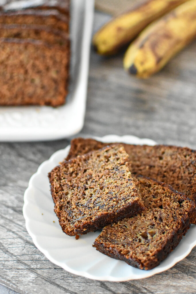 banana bread on a plate, with more banana bread in the background