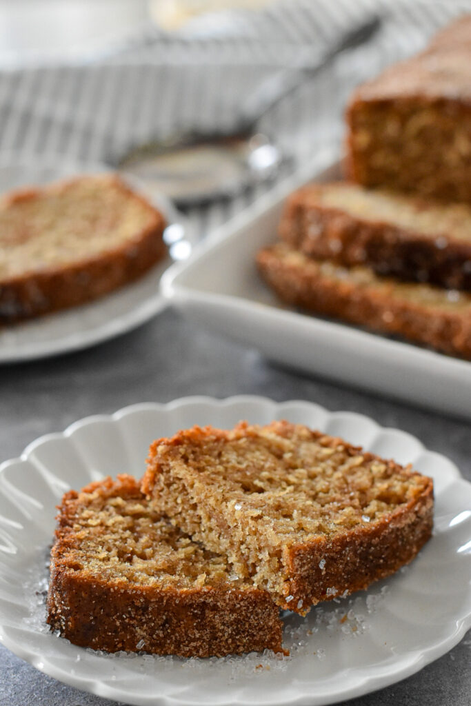 A close-up of apple cider loaf cake sprinkled with cinnamon sugar, highlighting its sweet, spiced coating