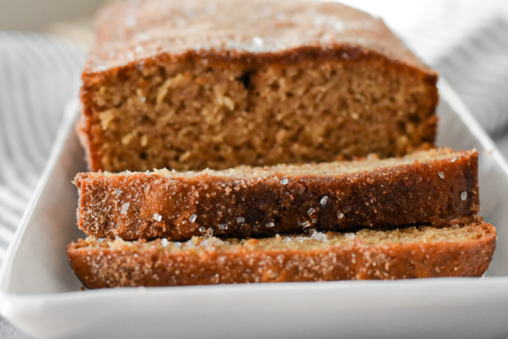 Close-up of a moist apple cider loaf cake slice, showing fluffy layers infused with spiced apple cider flavors.