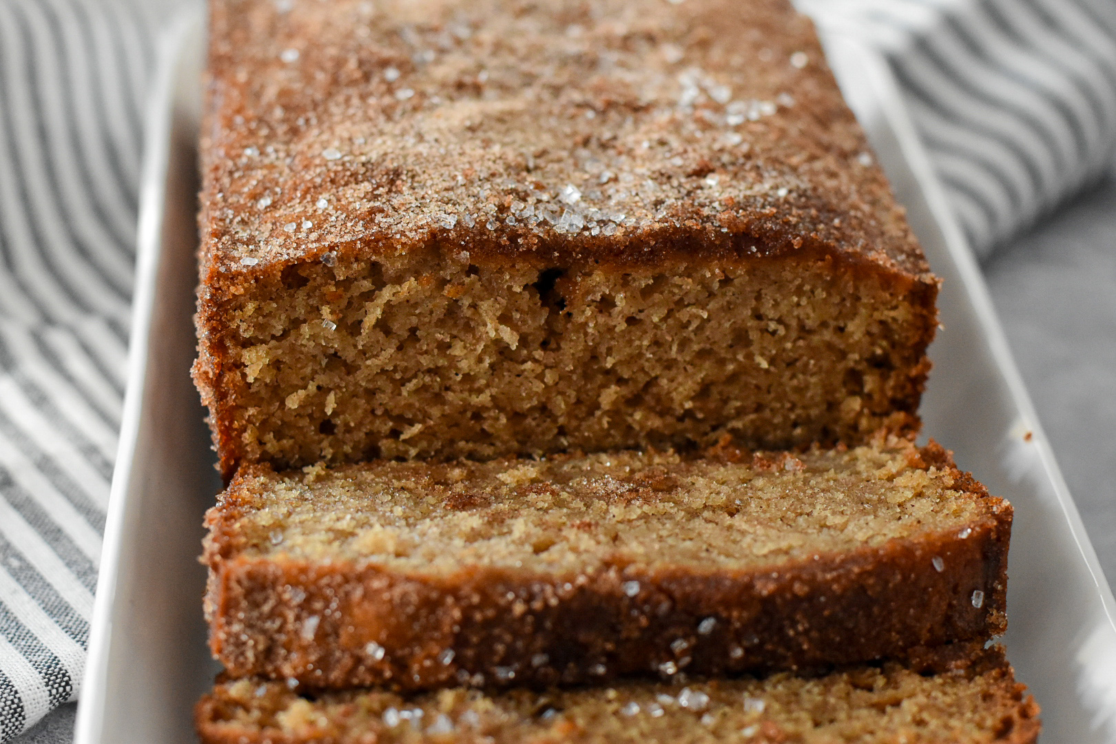 Top-down view of a golden-brown apple cider loaf cake, evenly dusted with cinnamon sugar for a perfect fall treat.