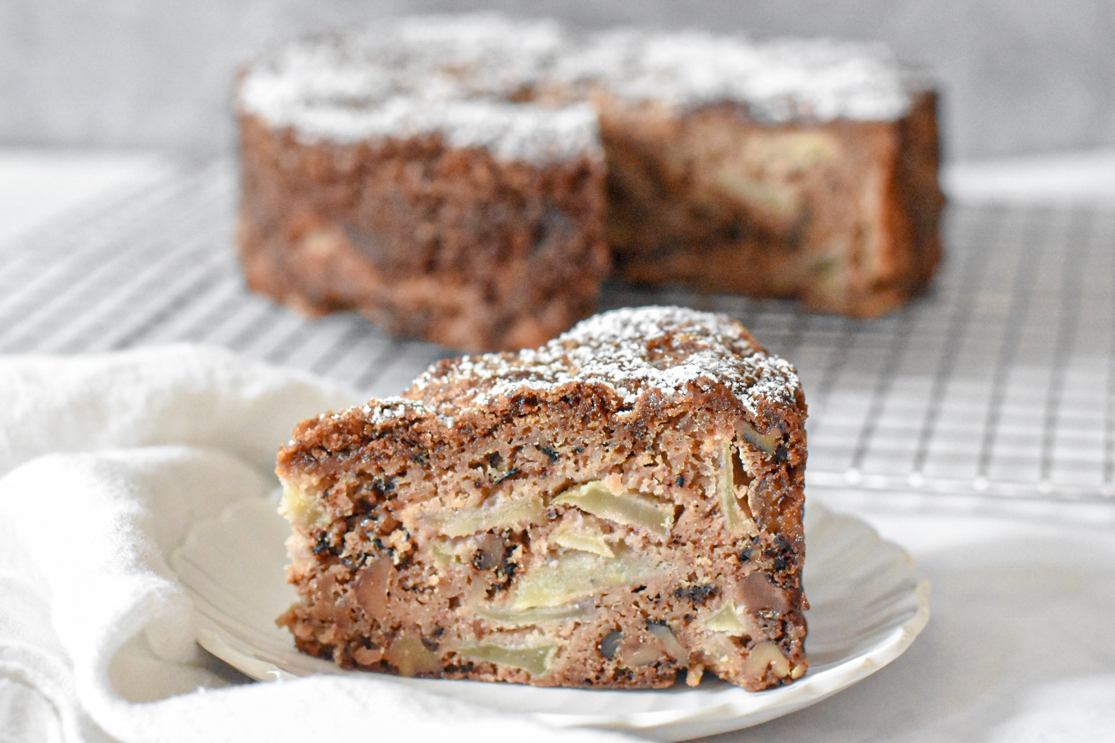 Tender and moist apple spice snacking cake on a cooling rack, slice of tender apple spice cake