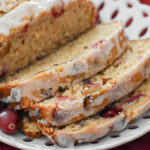 sliced cranberry orange bread with maple glaze on a plate
