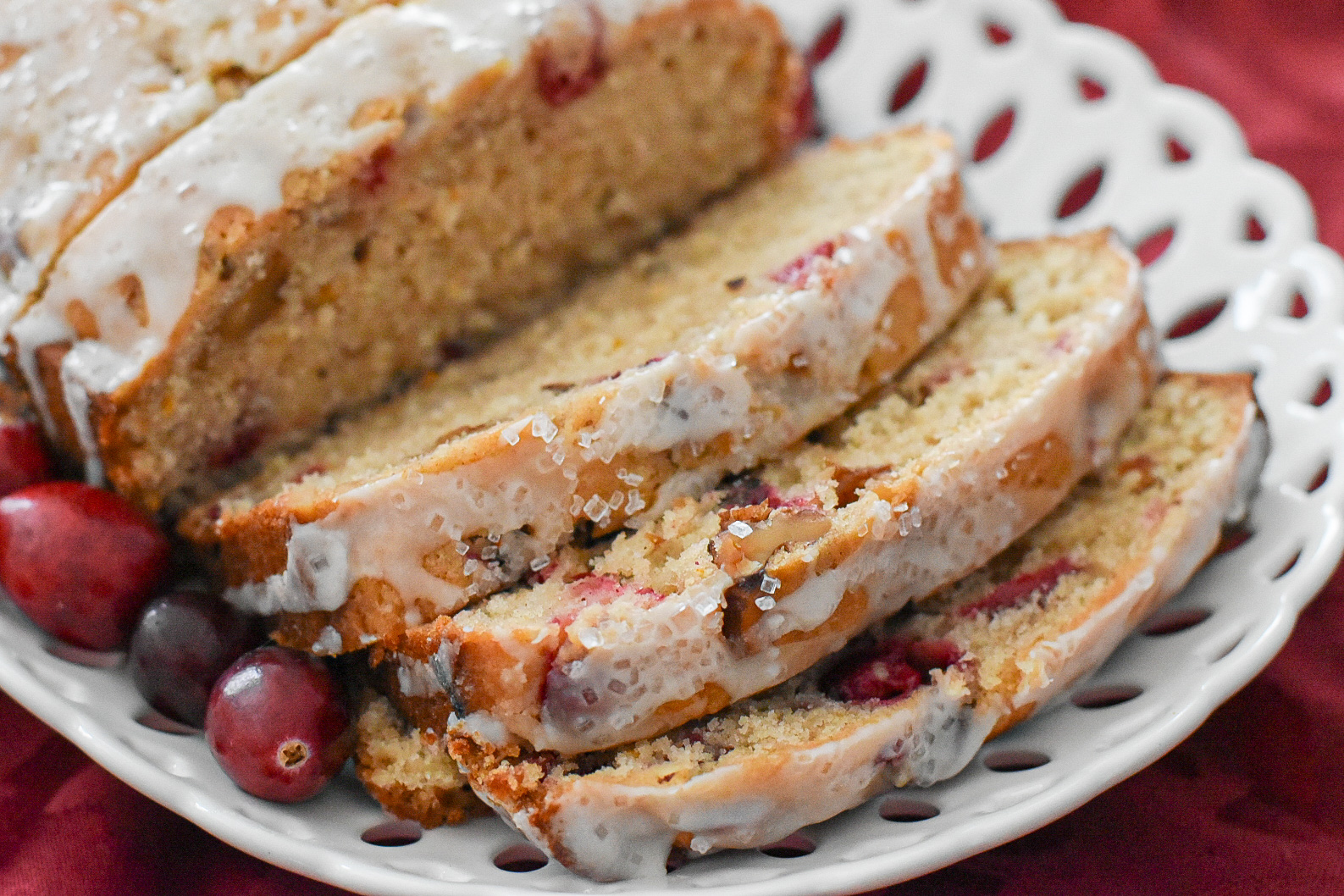 sliced cranberry orange bread with maple glaze on a plate