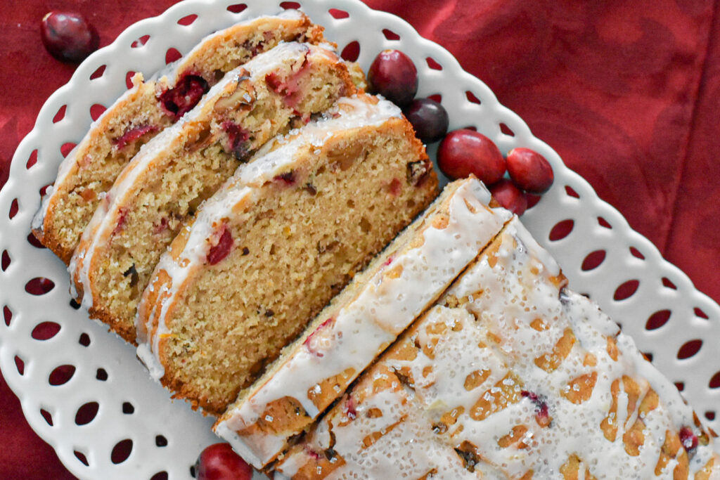 sliced cranberry orange bread with citrus glaze on a plate